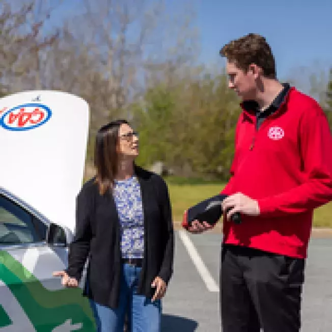 Customer and CAA employee standing in parking lot discussing EV cars