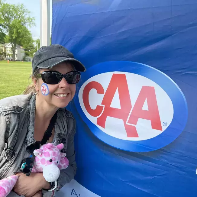 Woman posing beside a CAA banner at an event