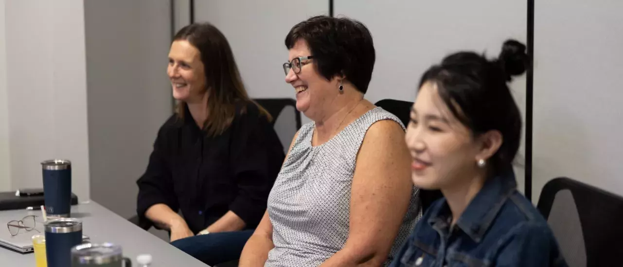 Three women smiling at a boardroom table