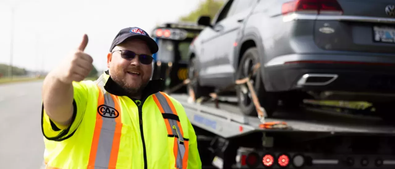 CAA roadside worker giving a thumbs up with a car in the background