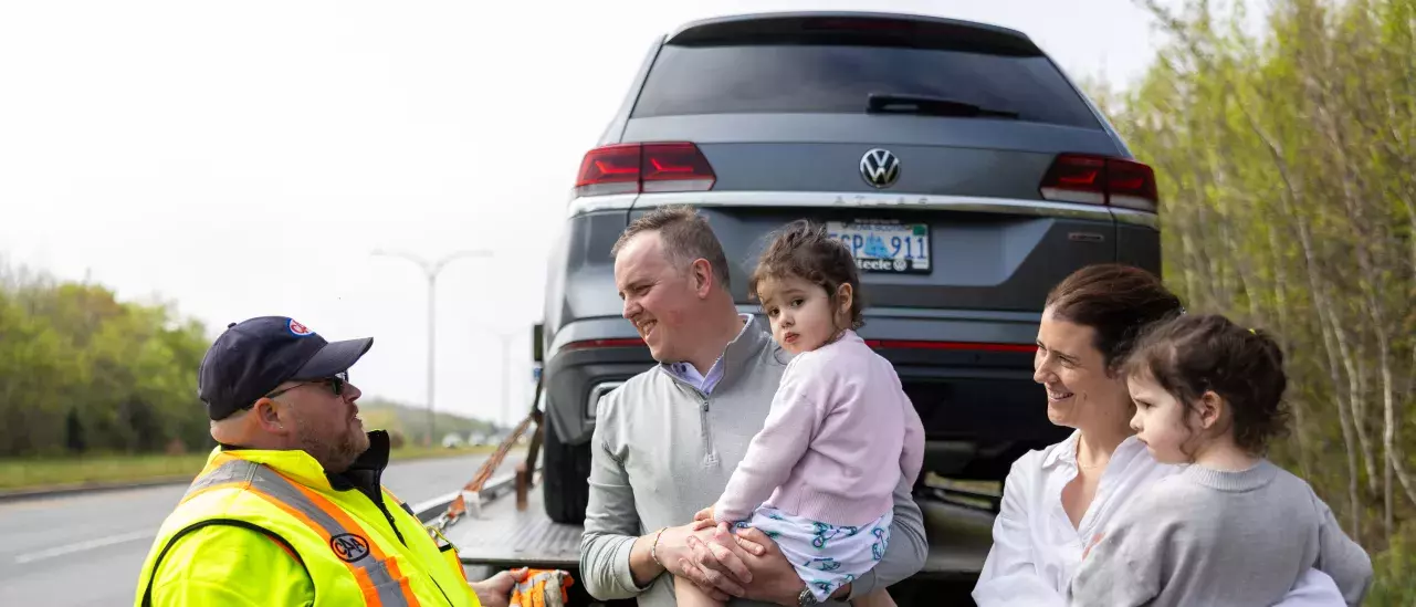 Family with tow truck driver and car on truck