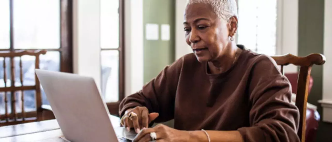 Woman sitting at her dining room table on her laptop. 