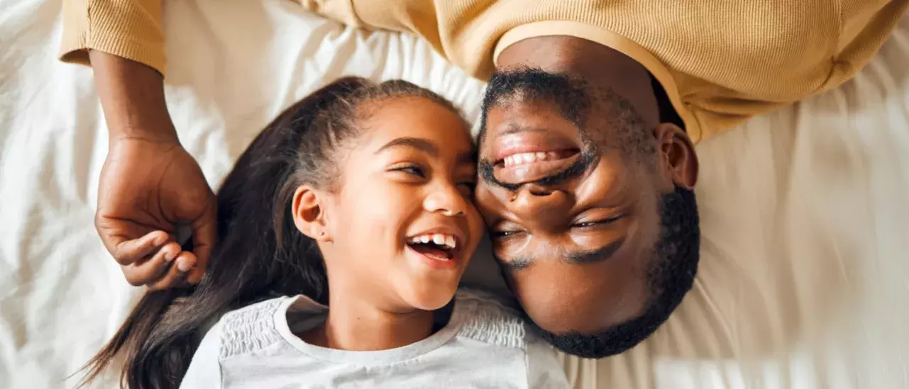 photo of father and daughter with heads side by side, but opposite one another, smiling at each other