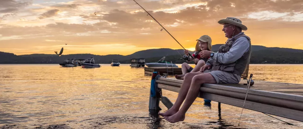 Two people fishing off a pier during sunrise