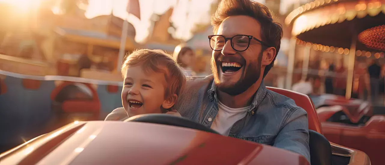 Cheerful father and son and have fun while driving a bumper car in an amusement park. 