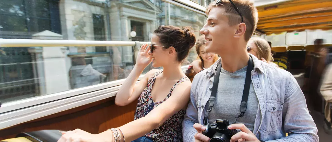 smiling couple with camera traveling by tour bus