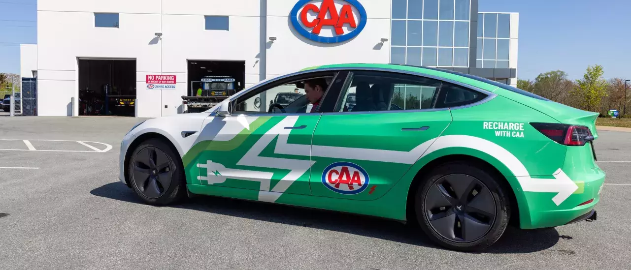 CAA's Tesla in front of a CAA builiding