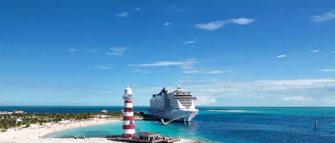 A MSC Cruises ship traveling in turquoise water and a sandy beach