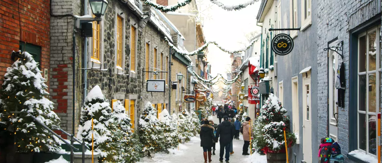 A couple walking down an old street with shops decorated with Christmas decorations
