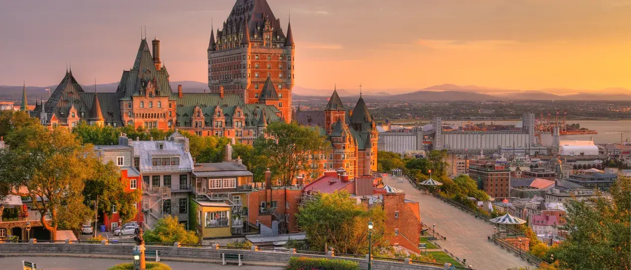 Sunset view of Quebec City with Château Frontenac, historic buildings, and the St. Lawrence River.