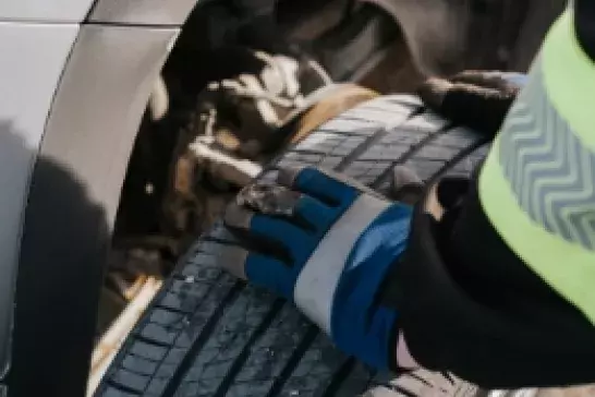 Close up shot of a worker wearing work gloves holding a tire