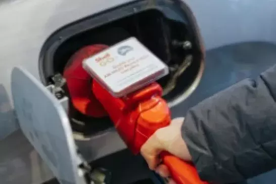 Hand holding a red gas pump putting gas in car