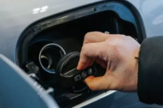 hand taking the cap off a gas tank of a vehicle 