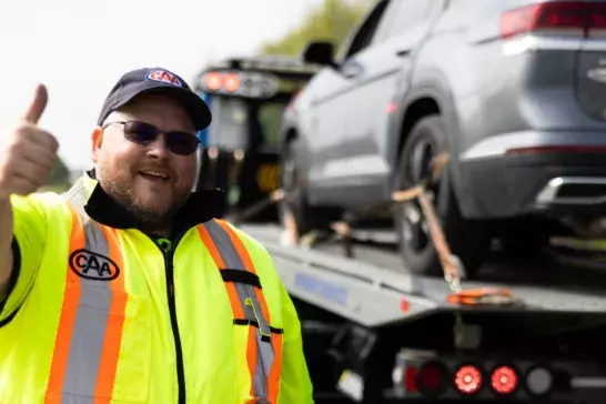 CAA roadside worker giving a thumbs up with a car in the background
