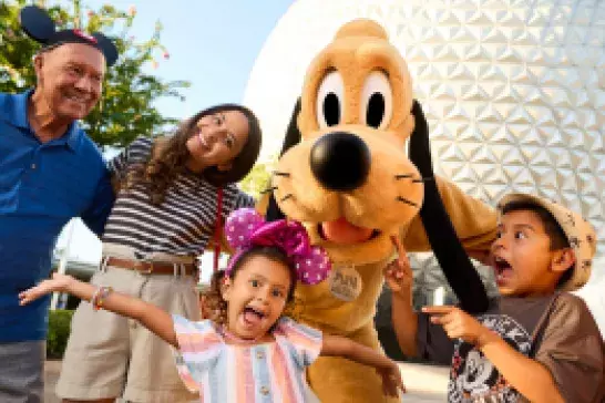 A family of four poses with Pluto in from of Dinsey's Epcot Centre.