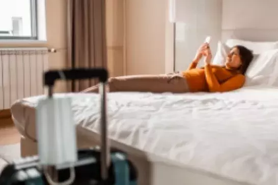 Person resting on bed after checking into hotel room