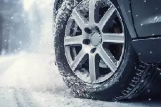 Image of a front tire turning on a snowy road surface