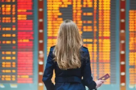 A woman standing in front of an airport flight status board