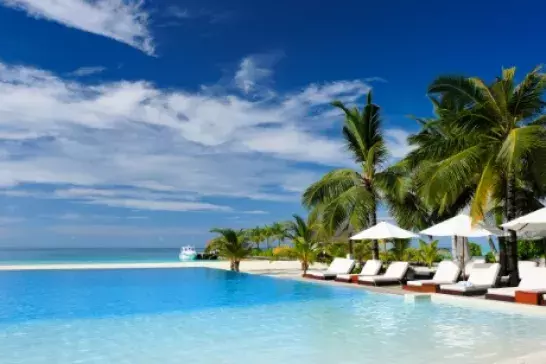 Tropical resort with palm trees and white beach chairs by a pool