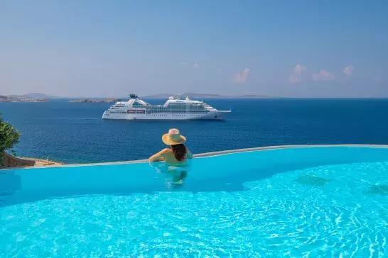 Woman in pool overlooking a Windstar ship