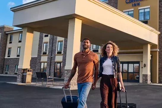 Couple walking out of the comfort inn with their suitcases