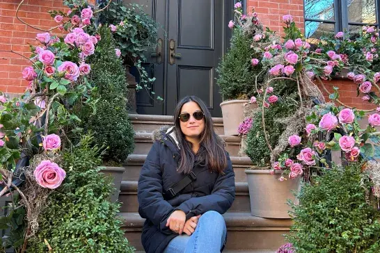Courtney sitting on the steps of someone's house in NYC covered in pink roses