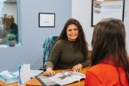 CAA Travel Advisor Delores sitting at her desk with a client
