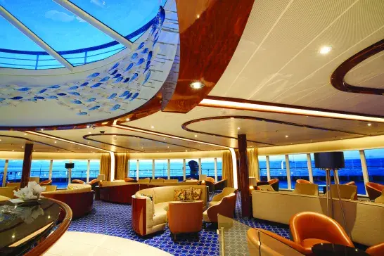 A lounging area on a Seabourn ship with a skylight and a view of the water from the windows