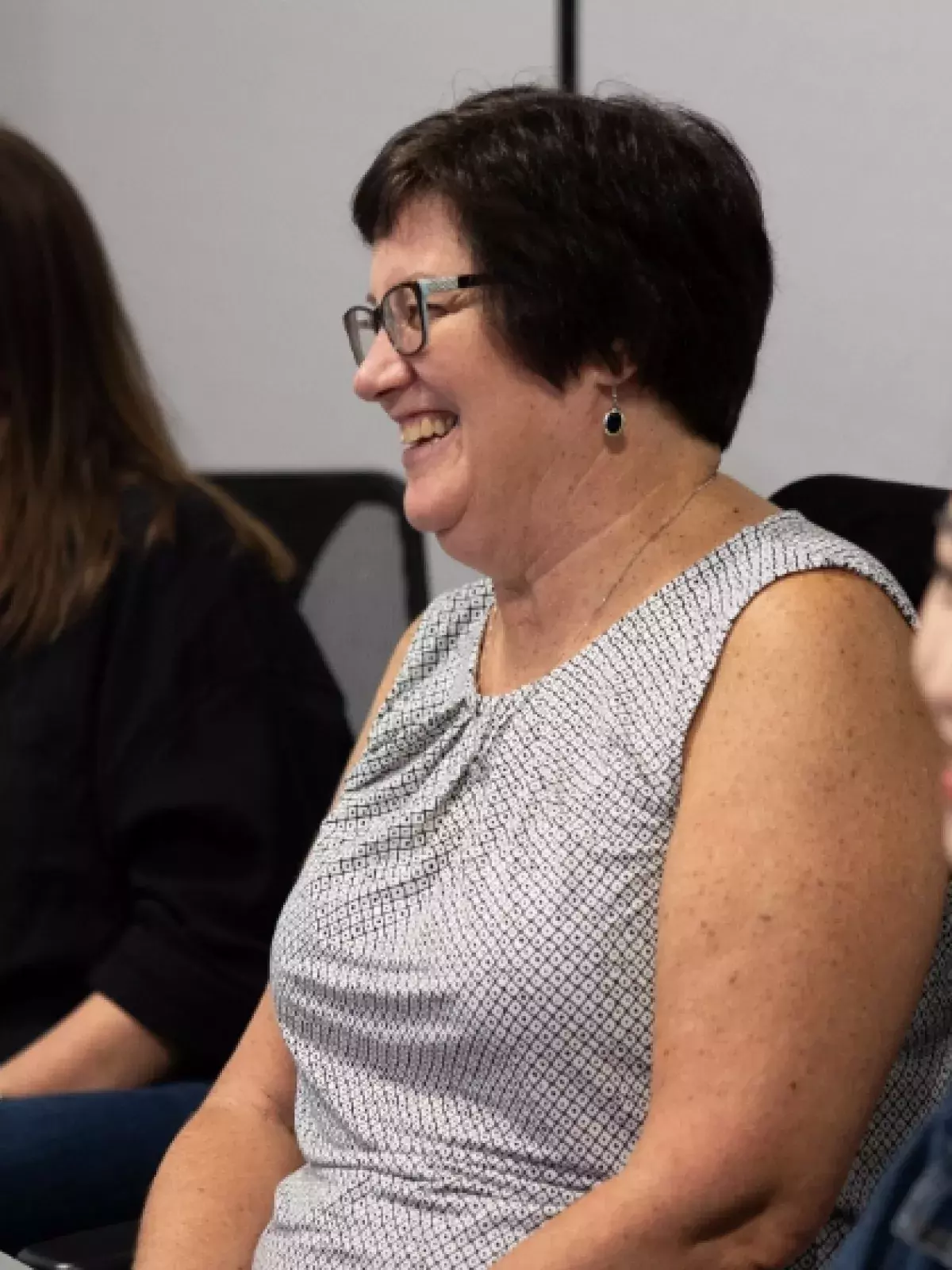 Three women smiling at a boardroom table