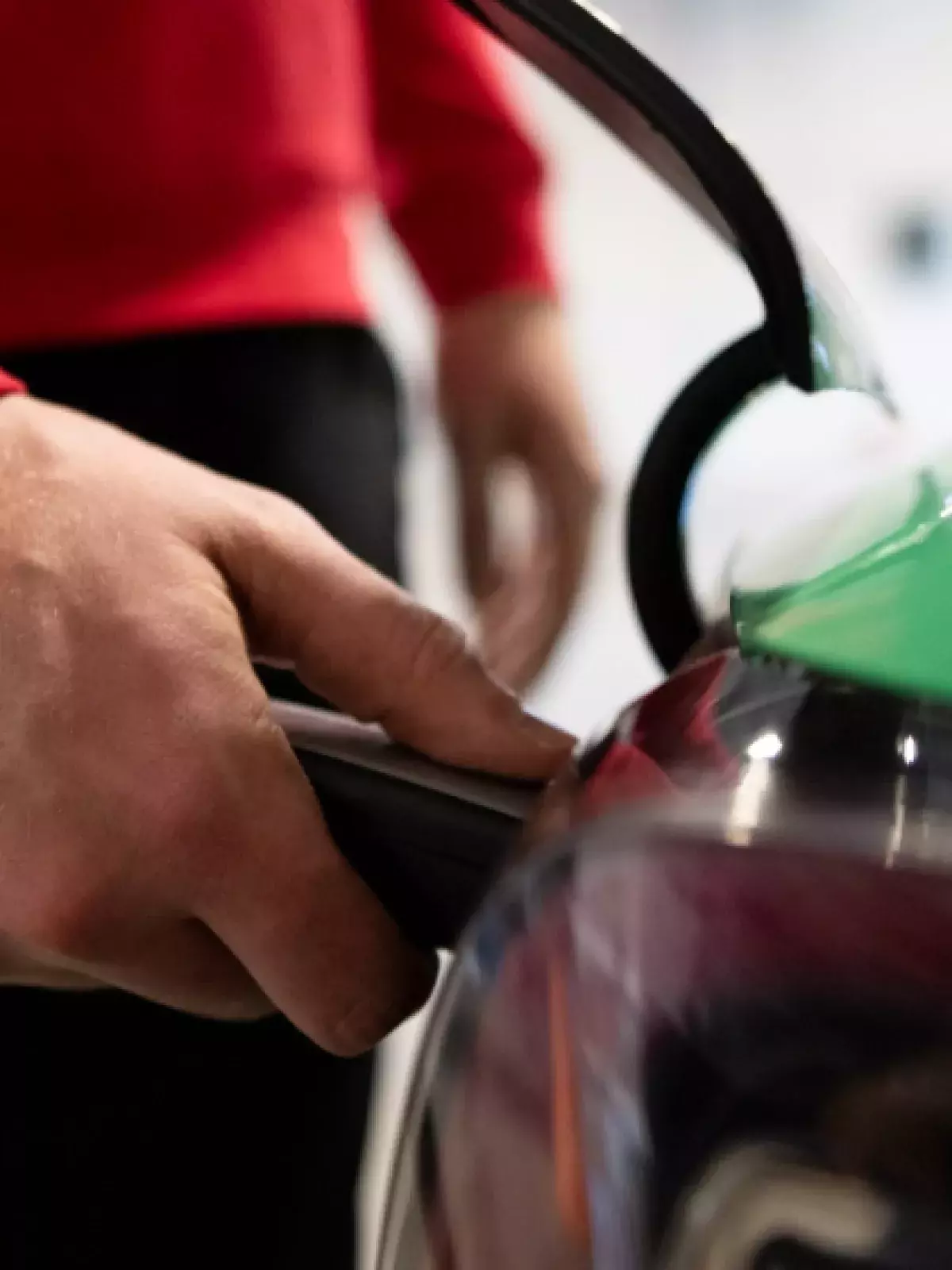 Close up of a hand holding an electric vehicle charger to a car