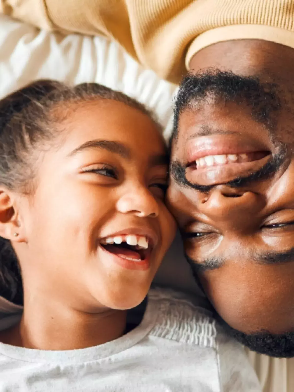 photo of father and daughter with heads side by side, but opposite one another, smiling at each other
