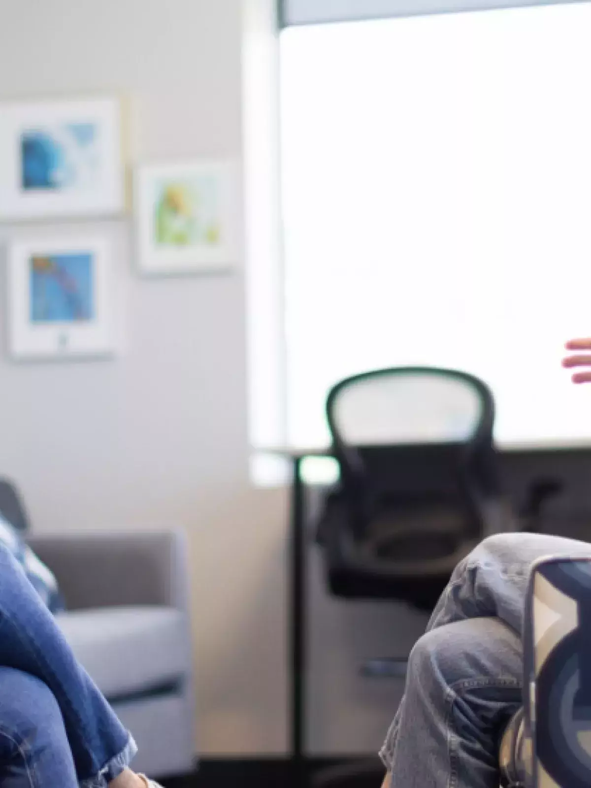Two females sitting in arm chairs facing each other, smiling, having a conversation