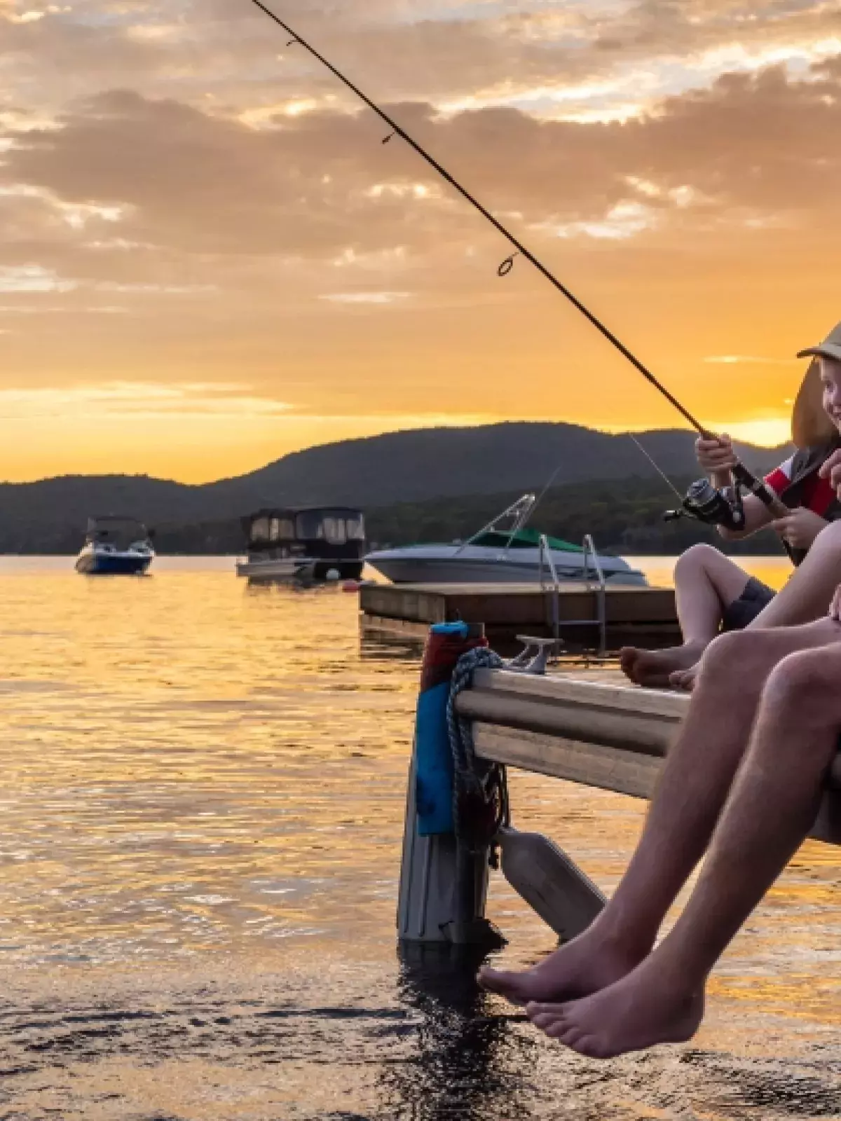 Two people fishing off a pier during sunrise