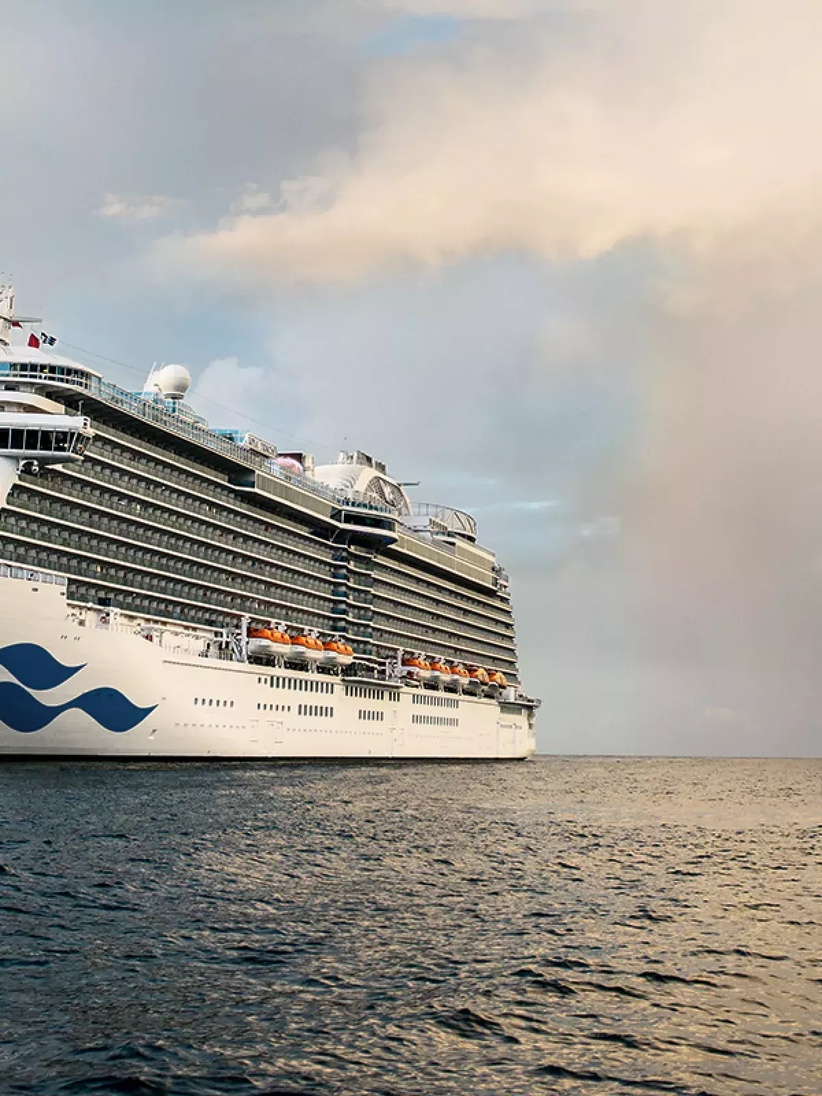 A cruise ship sailing at sea with a rainbow in the background