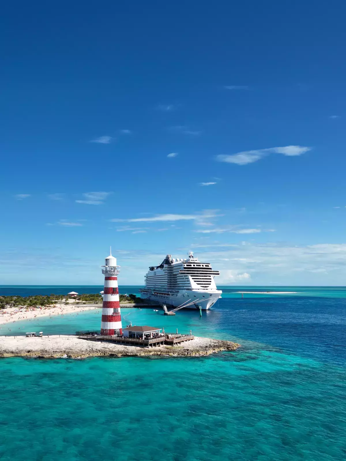 A MSC Cruises ship traveling in turquoise water and a sandy beach