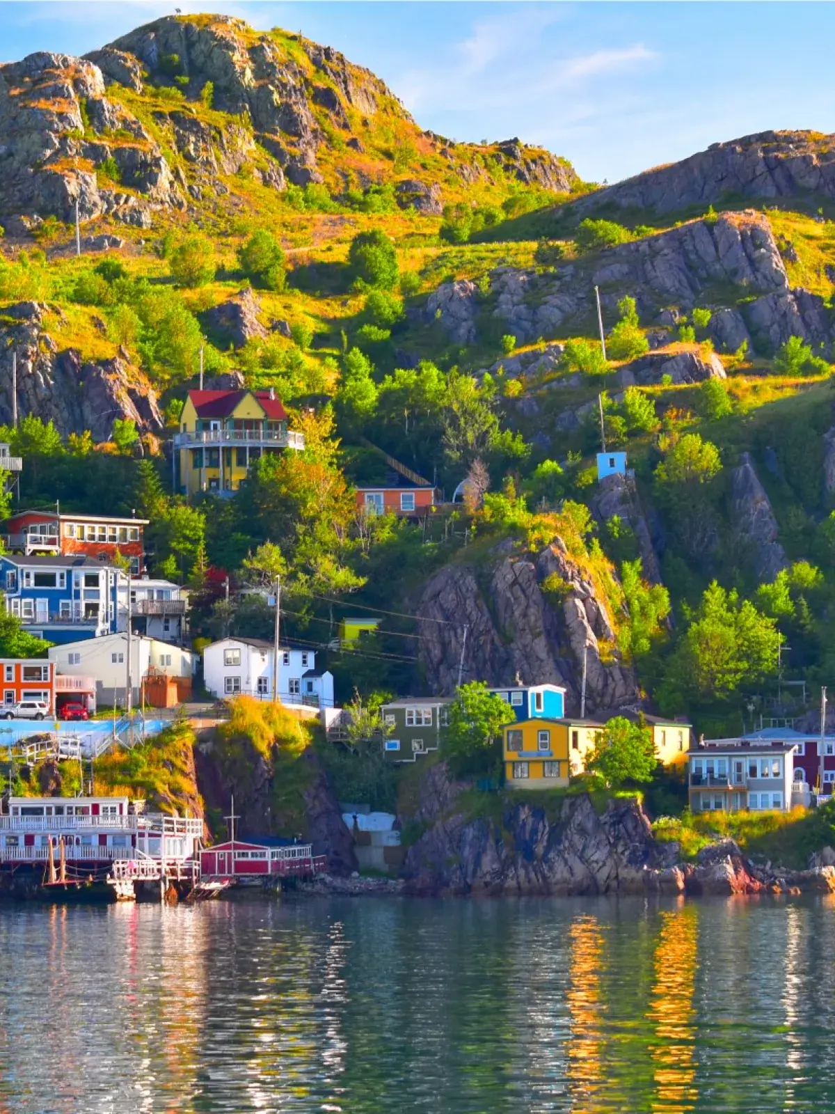 A coastal village with colorful houses built on a rocky hillside, reflecting in the calm water below.