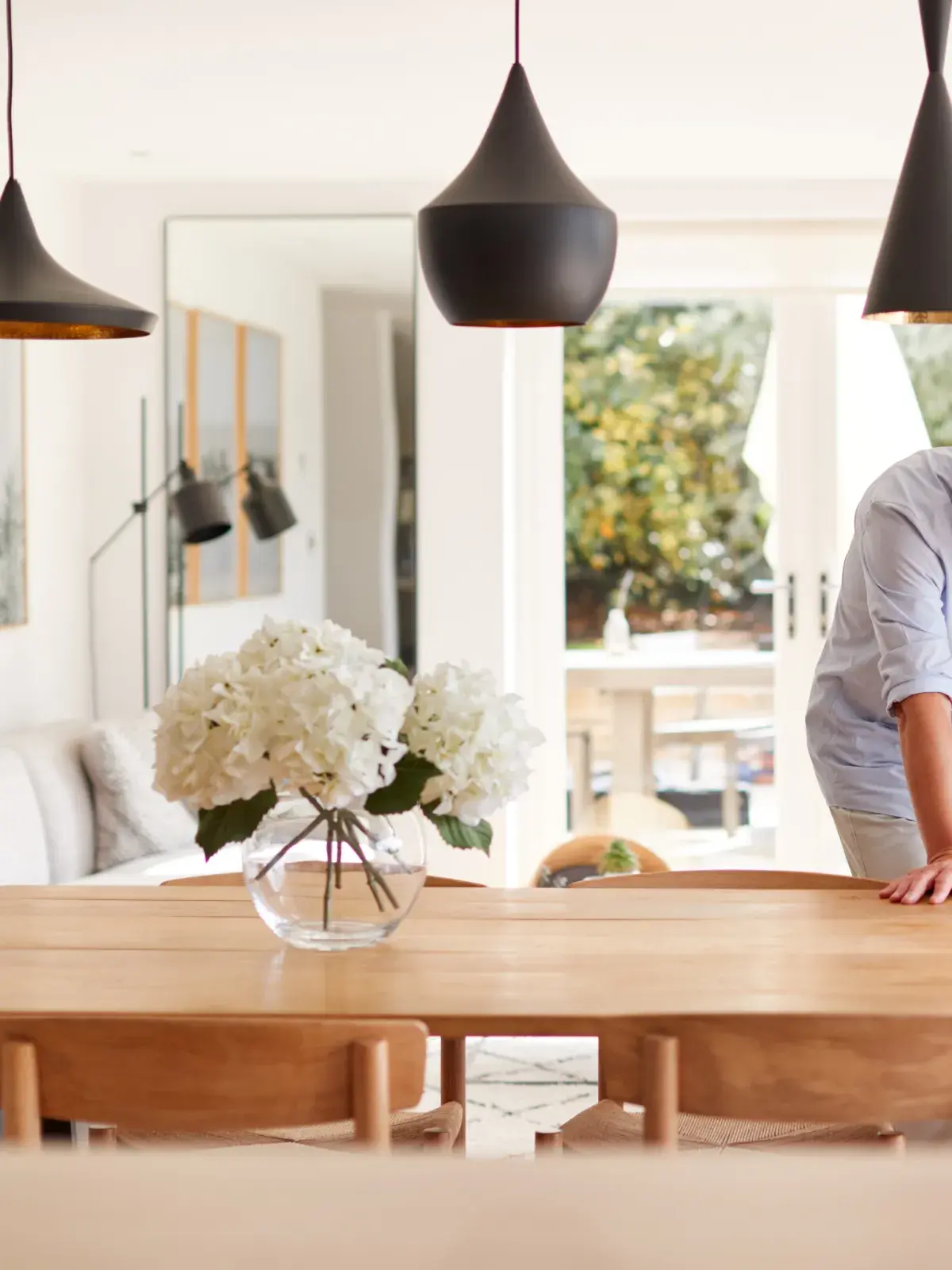 Two adults look at a smartphone together at a dining table in a bright, modern home.