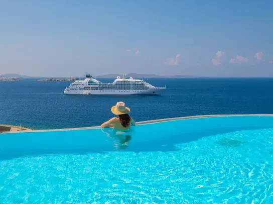 Woman in pool overlooking a Windstar ship