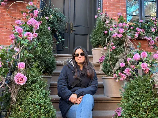 Courtney sitting on the steps of someone's house in NYC covered in pink roses