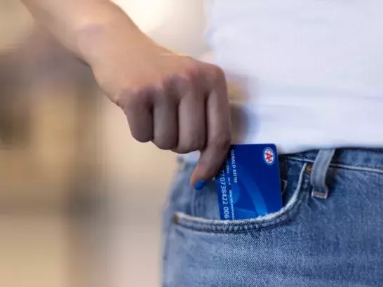 hand with blue nailpolish taking out a blue membership card from blue jeans pocket