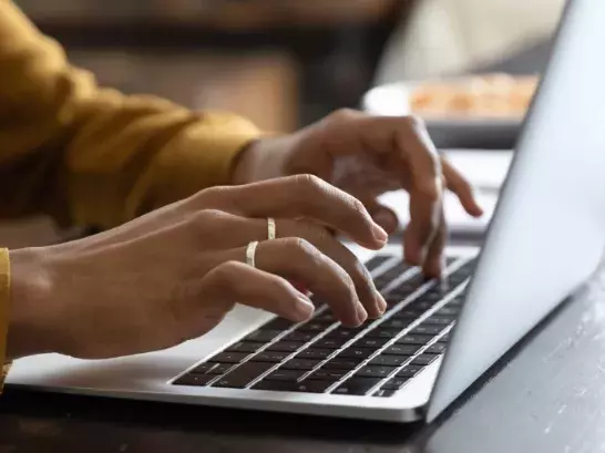 Close up shot of two hands typing on a computer