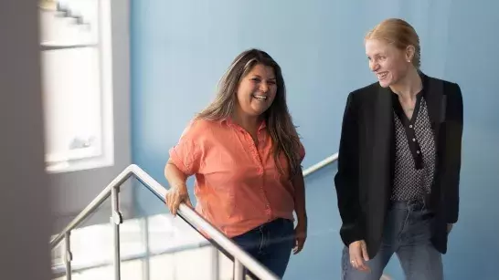 Two people smiling at each other walking up a staircase