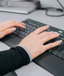 two hands typing on a black keyboard 