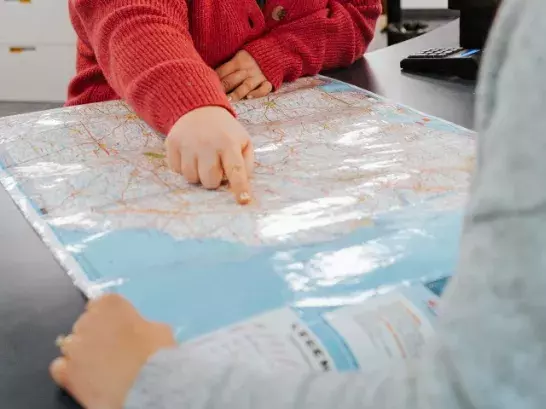 hand pointing to a spot on a map with red sweater pictured. 