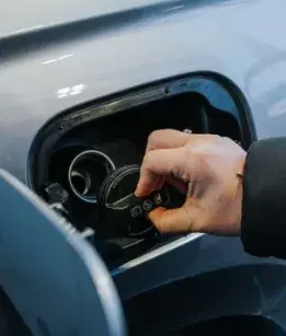 hand taking the cap off a gas tank of a vehicle 