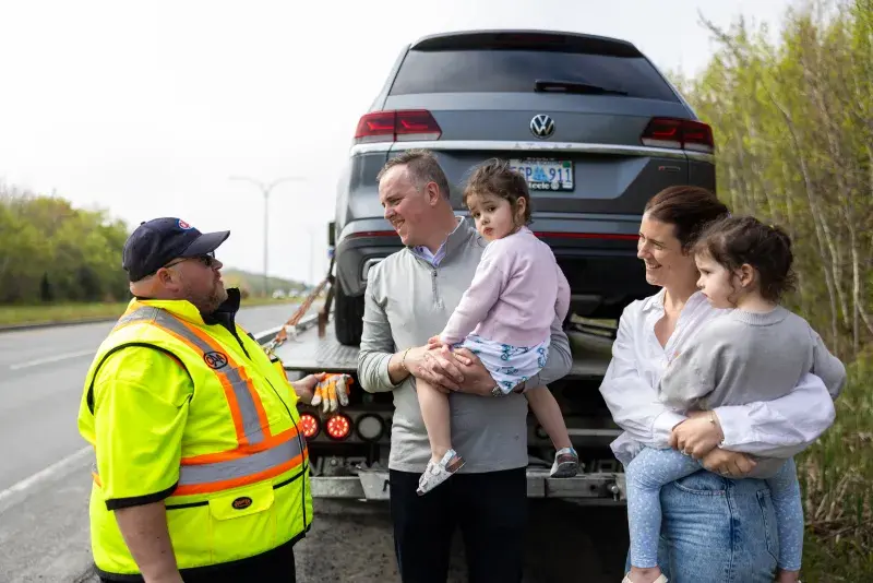 Family with tow truck driver and car on truck