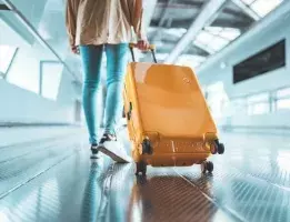Person walking through airport with yellow luggage