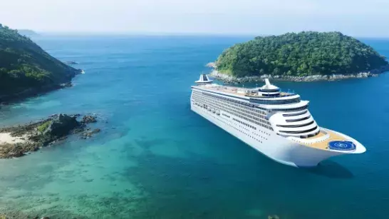 White cruise ship sailing between two lush green islands