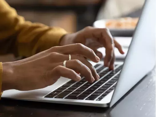 Two hands working on a laptop