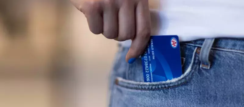 Hand with blue nail polish pulling a blue membership card out of a jeans pocket